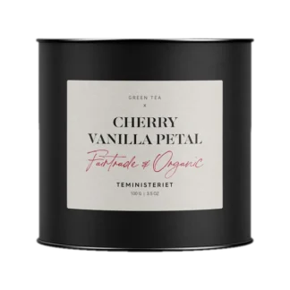 Puszka herbaty Teministeriet Cherry Vanilla Petal o wadze 100g, na białym tle. Organiczna zielona herbata o smaku wiśni i wanilii, certyfikowana Fairtrade, zapakowana w elegancką czarną puszkę