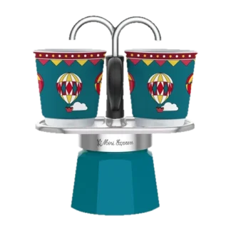 Ekspres Mini Express Bialetti w wersji oktanowej z kolekcji Wonderland. Zestaw zawiera kawiarnię na dwie filiżanki oraz dwie kolorowe filiżanki z motywem balonów na niebieskim tle, umieszczone bezpośrednio nad miejscem nalewania kawy.